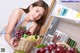 A woman holding a basket full of fruit in a kitchen.