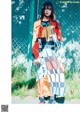 A woman standing in front of a chain link fence.