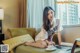 A woman sitting on a couch with a cup of coffee.