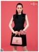 A woman in a black dress holding a pink purse.