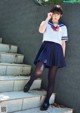 A woman in a school uniform is posing for a picture.