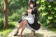 A woman in a maid outfit sitting on a bench in a park.