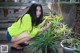 A woman kneeling down next to a potted plant.