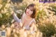 A woman in a white dress sitting in tall grass.