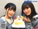 Two young women holding a birthday cake with a number five on it.